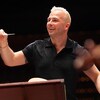 Un homme blond dirige un orchestre 