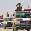 Des combattants yéménites font un salut depuis la plage arrière d'un véhicule.