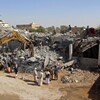 Des Yéménites sur le site d'un bâtiment ciblé par un bombardement aérien.