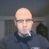 L'homme au crâne rasé, cigarette au bec, a une toile d'araignée sur la gorge.