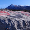 Du ciment avec des symboles en peinture et des montagnes enneigées en arrière-plan.