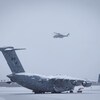 Un avion posé au sol l'hiver et un hélicoptère dans les airs le 13 février 2023 à Whitehorse, au Yukon.