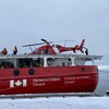 Un hélicoptère rouge est sur un bateau.