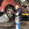 Jano Roussel installe un pneu sur un véhicule dans son garage.