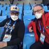 Un homme en noir avec une casquette de baseball assis à côté d'un homme en rouge