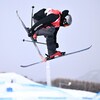 Un skieur canadien effectue une manœuvre en tenant son ski droit.