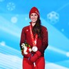 Ivanie Blondin qui sourit sur le podium avec sa médaille d'argent au cou et un bouquet de fleurs dans les mains. 