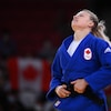 Une judoka se tient la ceinture à la fin de son combat, et regarde en l'air.