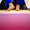 Les pieds de deux judokas sont bien campés sur un tatami. 