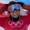 Meryeta O'Dine, tout sourire, tient le drapeau canadien dans son dos après sa 3e place en snowboard cross.