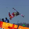 Durant un saut en pleine épreuve de demi-lune, Cassie Sharpe agrippe son ski droit derrière son dos avec sa main droite.