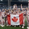 Les joueuses de l'équipe prennent une photo avec le drapeau canadien. 