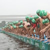 Des athlètes sont au bord de l'eau, sur le point de sauter.