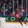 Un hockeyeur canadien lève les bras pour célébrer un but devant un adversaire letton.