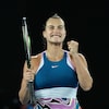 La joueuse de tennis Aryna Sabalenka sourit à pleines dents en serrant le poing gauche.