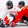 Un joueur de l'équipe canadienne de parahockey contrôle la rondelle devant un adversaire de la Chine. 