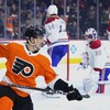 Un joueur de hockey célèbre un but à l'avant plan alors que trois joueurs de l'équipe adverse sont déçus à l'arrière.