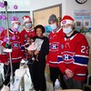 Quatre joueurs de hockey entourent une mère avec son bébé dans une chambre d'hôpital.