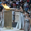 Une femme allume un flambeau à partir d'une vasque au cours d'une cérémonie. 