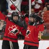 Deux joueuses de hockey lèvent les bras au ciel après avoir inscrit un but.