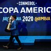 Il transporte le trophée sur une scène où est affichée le logo de la Copa América.