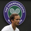 Concentré, il regarde la balle devant un logo de Wimbledon.