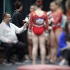 Un entraîneur parle à des gymnastes qui sont floues sur la photo.
