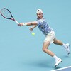 Un joueur de tennis s'étire pour tenter de frapper la balle du revers de la raquette.