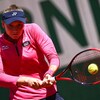 Une joueuse de tennis fixe intensément des yeux la balle, qu'elle s'apprête à frapper avec sa raquette.