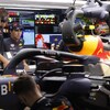 Des ingénieurs travaillent sur une voiture de Red Bull dans un garage.