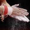 Un gymnaste applique de la poudre de magnésium sur ses mains. 