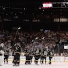 Réunis au centre de la patinoire, des hockeyeurs lèvent leur bâton en direction des gradins.