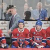 L'entraîneur est derrière ses joueurs sur le banc et porte la main à sa tête.