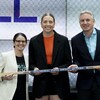 Elle tient un bâton de hockey aux côtés d'une joueuse et d'un dirigeant.