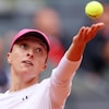 Une joueuse de tennis au service lance la balle et regarde en l'air.
