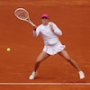 Une joueuse de tennis frappe une balle sur un court en terre battue.
