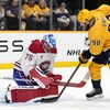 Un gardien effectue un arrêt devant un adversaire et un coéquipier. 