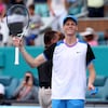 Un joueur de tennis sourit et tient sa raquette dans sa main droite.