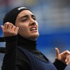 A woman glances at the scoreboard as she crosses the finish line.