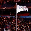 Un drapeau affichant les cinq anneaux olympiques flotte au vent.