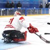 Un gardien de parahockey canadien se dresse devant un attaquant américain en tir de pénalité.