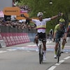 Un cycliste célèbre sa victoire après avoir devancé deux rivaux.