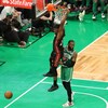 Un basketteur effectue un dunk devant un rival.