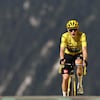 Un cycliste portant un maillot jaune arrive au sommet d'une colline.