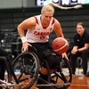 Une basketteuse en fauteuil roulant regarde un ballon.