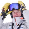 Une skieuse a les mains gantées sur ses lunettes, et sourit pour la photo.