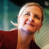 Kirsty Coventry, vêtue d'un tailleur, écoute une conférence. 