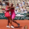 Deux joueuses de tennis se sautent dans les bras l'une de l'autre en souriant.