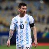 Lionel Messi marche sur un terrain de soccer et regarde devant lui. 