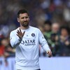 Un joueur de soccer fait un geste de la main en souriant pendant un match.